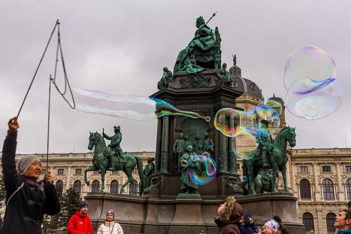 Mujer que entretiene con burbujas a niños que pasean en la Plaza María Teresa de Viena, Austria. Abril de 2023.