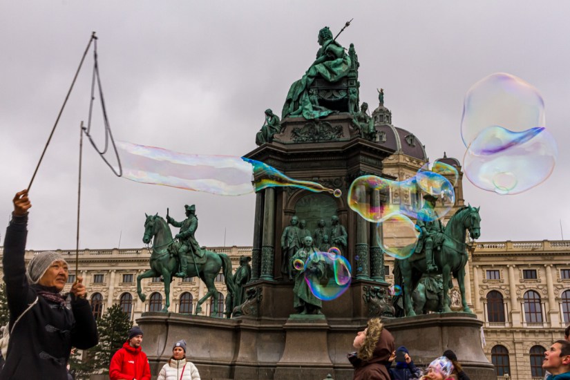 Mujer que entretiene con burbujas a niños que pasean en la Plaza María Teresa de Viena, Austria. Abril de 2023.